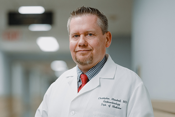 A doctor in a white coat, standing in the hallway of a medical facility