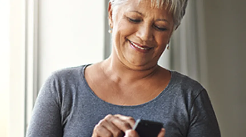 Smiling woman with short gray hair checking phone
