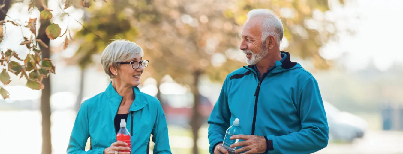 A senior couple walks in a park and represent one of the methods of lowering risk of stroke.
