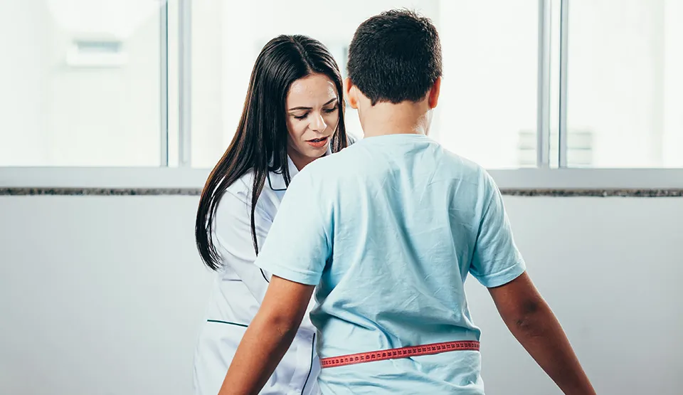 A doctor measuring the waist of a child patient.