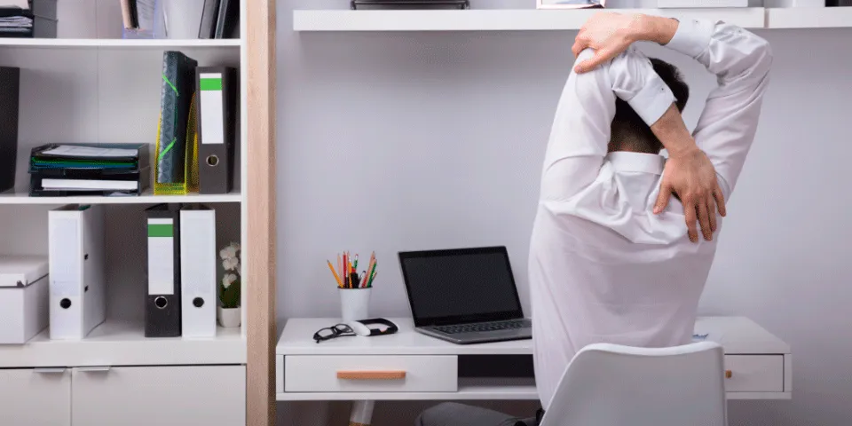A worker at a desk is shown stretching from behind.