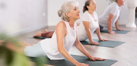 A group of two women and one man practice yoga together.  