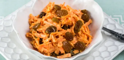 carrot and raisin slaw in a white serving bowl