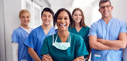 A group of confident and smiling nurses in a hospital hallway.