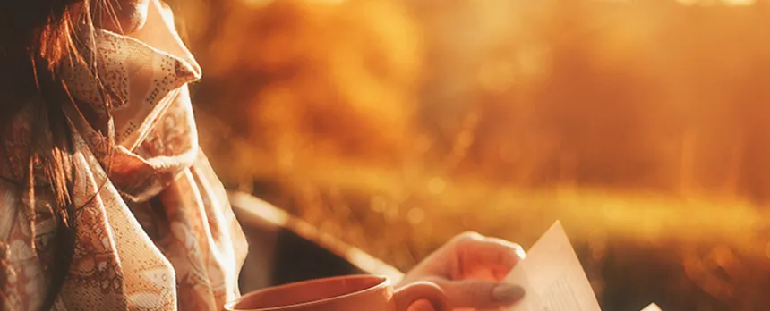 girl relaxing drinking tea and reading a book in the sunlight
