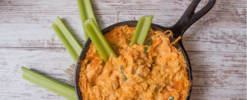 Skinny buffalo chicken dip in a skillet served with celery