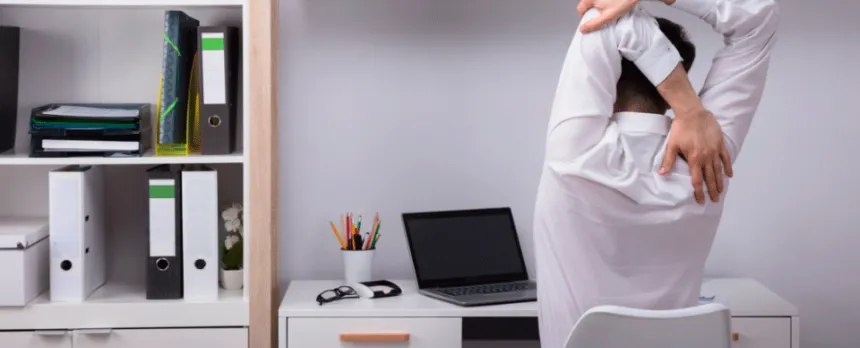 A worker at a desk is shown stretching from behind.